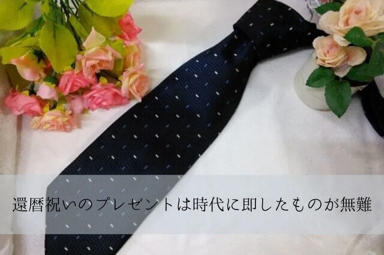 紺色のネクタイとその周りに置かれた白やうすピンクの薔薇の花束