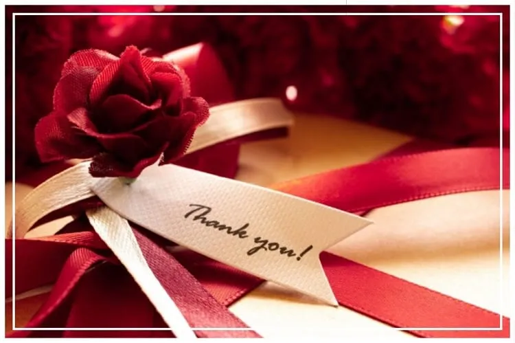 プレゼントボックスの上に置かれた赤い一輪の薔薇とthankyouと書かれたリボン